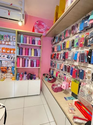 Interior da loja Império Di Maria com prateleiras de acessórios de celular e cosméticos